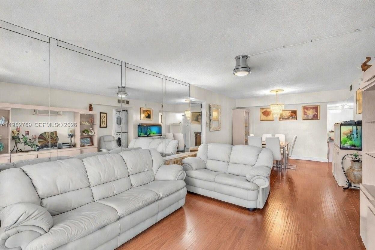 A living room features white leather sofas, mirrored walls, and hardwood flooring — 4160 Inverrary Dr # 308, Lauderhill FL 33319, LAUDERHILL, FL