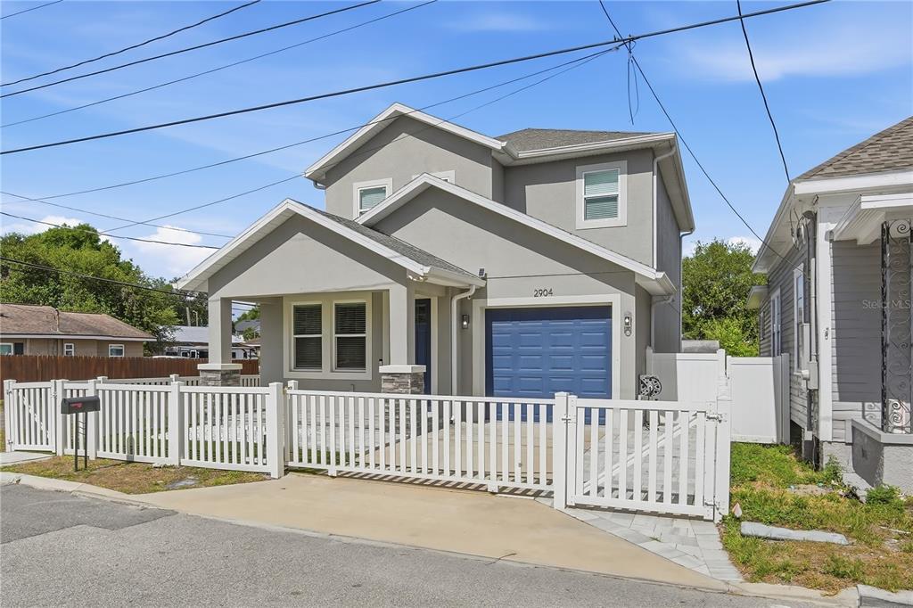 A two-story house with a blue garage door and a white picket fence — 2904 BANZA STREET, TAMPA, FL