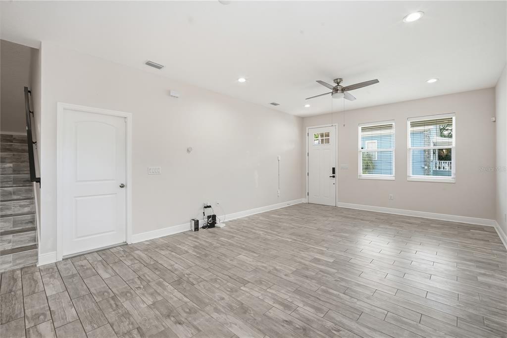 A bright living room features light gray wood-look tile flooring, white walls, and recessed lighting — 2904 BANZA STREET, TAMPA, FL