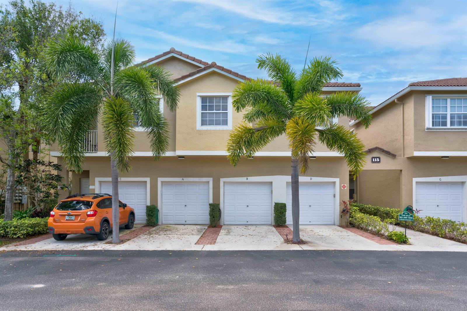 The exterior of a two-story townhouse complex features four garage doors and two palm trees — 115 Lighthouse Circle # B, Tequesta FL 33469, TEQUESTA, FL