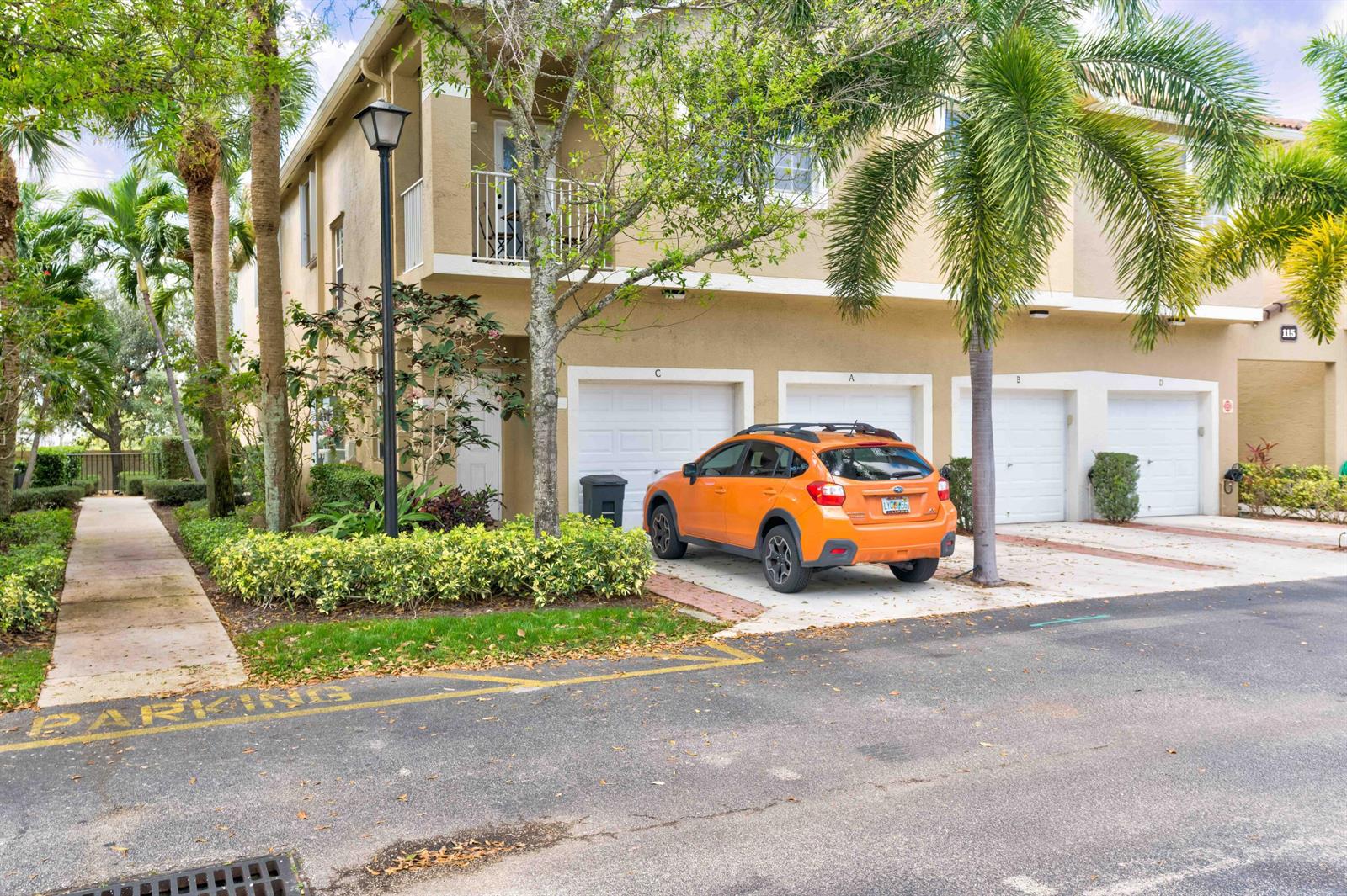 An orange SUV is parked in front of a two-story tan townhouse with multiple garages — 115 Lighthouse Circle # B, Tequesta FL 33469, TEQUESTA, FL