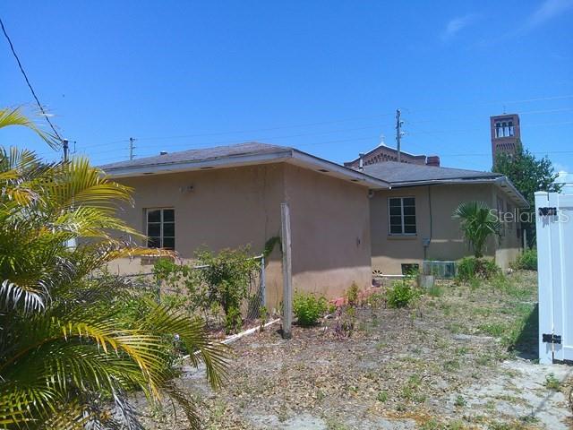 The exterior of a tan, single-story house with a flat roof and a nearby church tower — 2040 22ND AVENUE S, ST PETERSBURG, FL