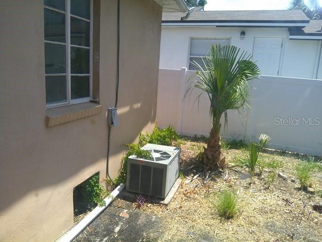 An exterior view shows a beige house wall with a window, an AC unit, and a palm — 2040 22ND AVENUE S, ST PETERSBURG, FL