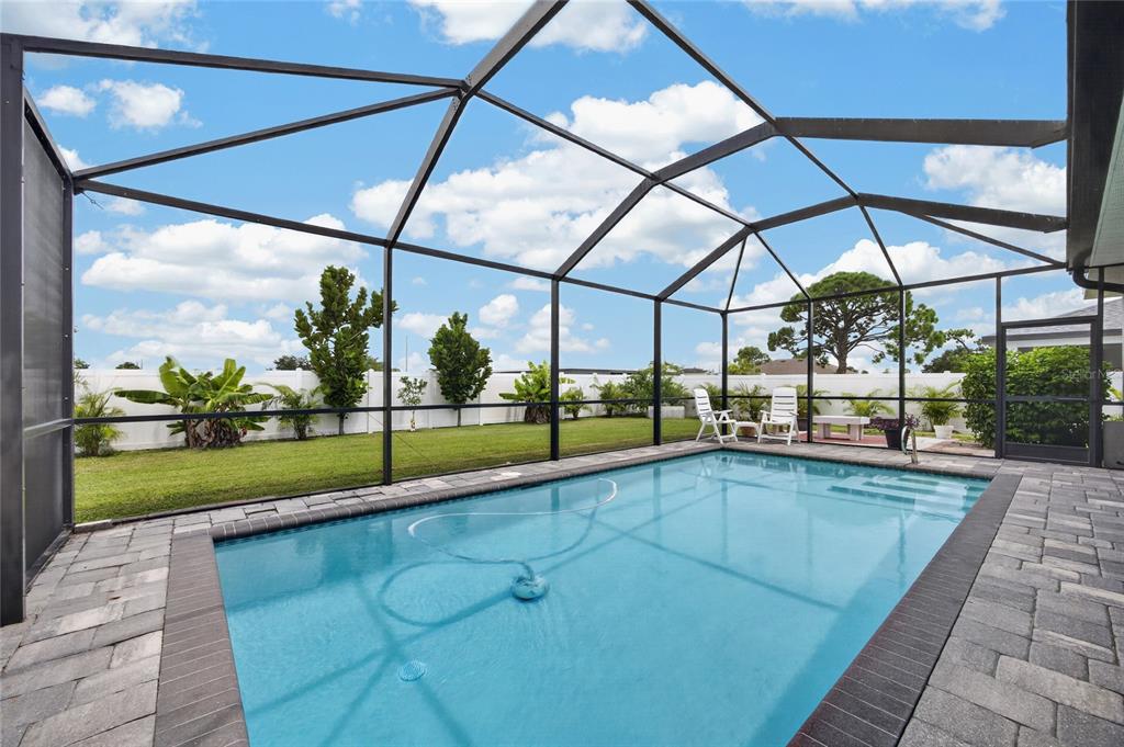 A swimming pool with a screen enclosure sits in a backyard with a white fence — 2909 NW 24TH AVENUE, CAPE CORAL, FL