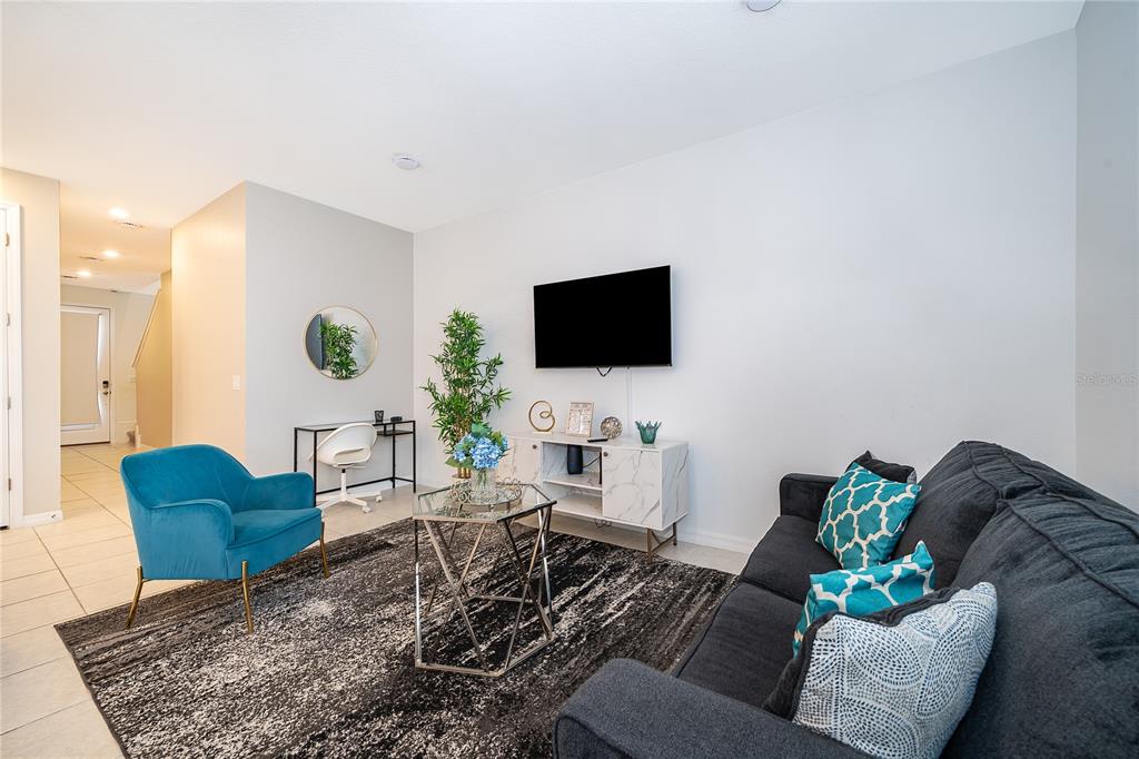 A living room features a dark sofa, a blue armchair, and a white media console — 1013 PLANTATION LANE, DAVENPORT, FL