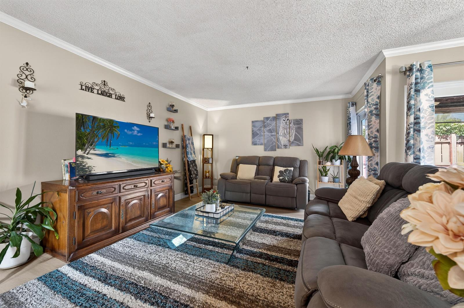 A living room features a television on a wooden console, gray sofas, and a rug — 124 Sherwood Circle # 11b, Jupiter FL 33458, JUPITER, FL