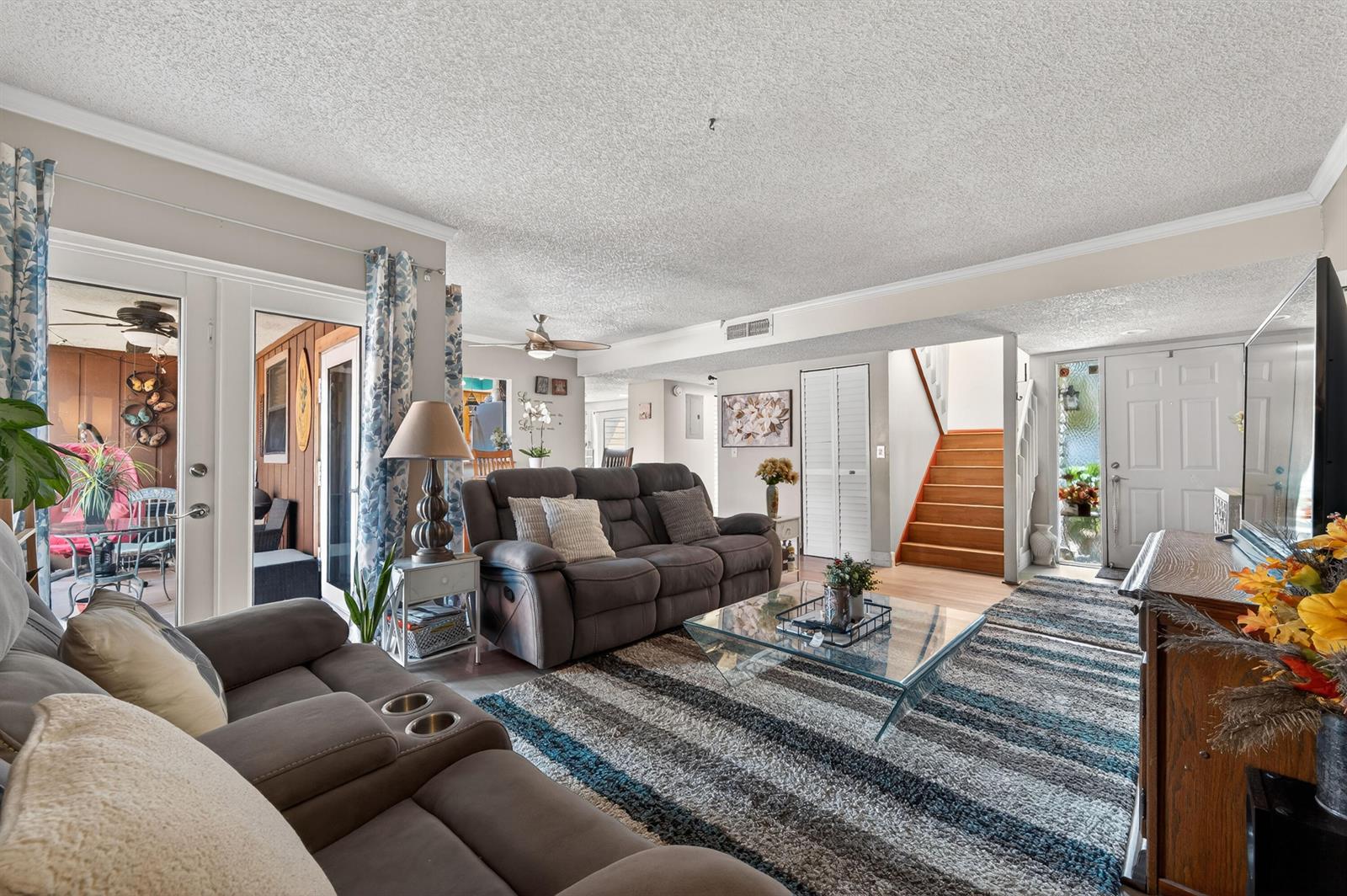 A living room features a gray sofa, a glass coffee table, and stairs leading upward — 124 Sherwood Circle # 11b, Jupiter FL 33458, JUPITER, FL