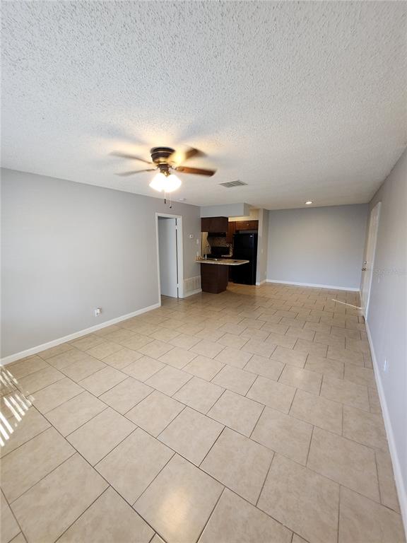 An open-concept living area features light-colored tile flooring, gray walls, and a small kitchen — 626 GOLDEN RAINTREE PLACE UNIT 626, BRANDON, FL