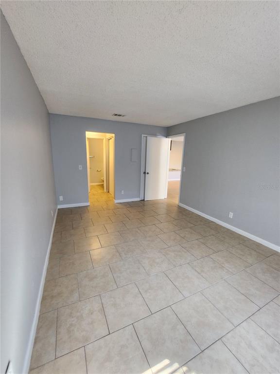 A room with light gray walls, beige tile flooring, and two open doorways — 626 GOLDEN RAINTREE PLACE UNIT 626, BRANDON, FL