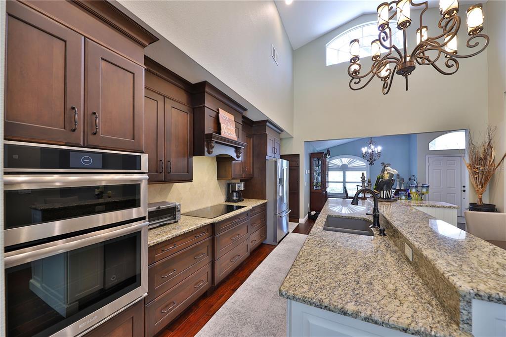 A kitchen with dark wood cabinets, granite countertops, stainless steel appliances, and a large island — 2578 EKANA DRIVE, OVIEDO, FL