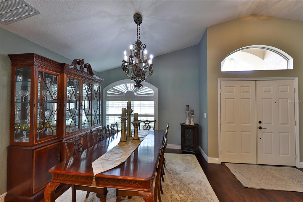 A dining room features a wooden table, a large hutch, and a chandelier near an entryway — 2578 EKANA DRIVE, OVIEDO, FL