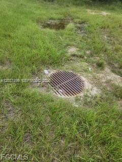 A circular metal storm drain grate sits in a patch of grass — 439 Naples AVE S, Lehigh Acres FL 33974, LEHIGH ACRES, FL