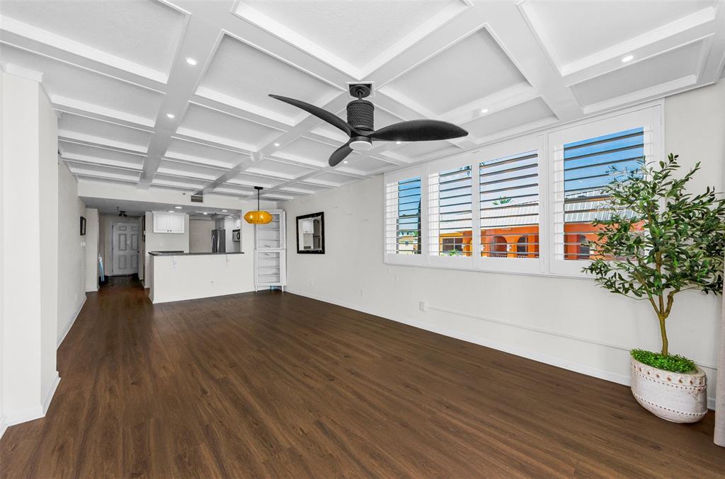 A living room with wood-look flooring, a coffered ceiling, and plantation shutters on the windows — 18201 GULF BOULEVARD UNIT 201, REDINGTON SHORES, FL
