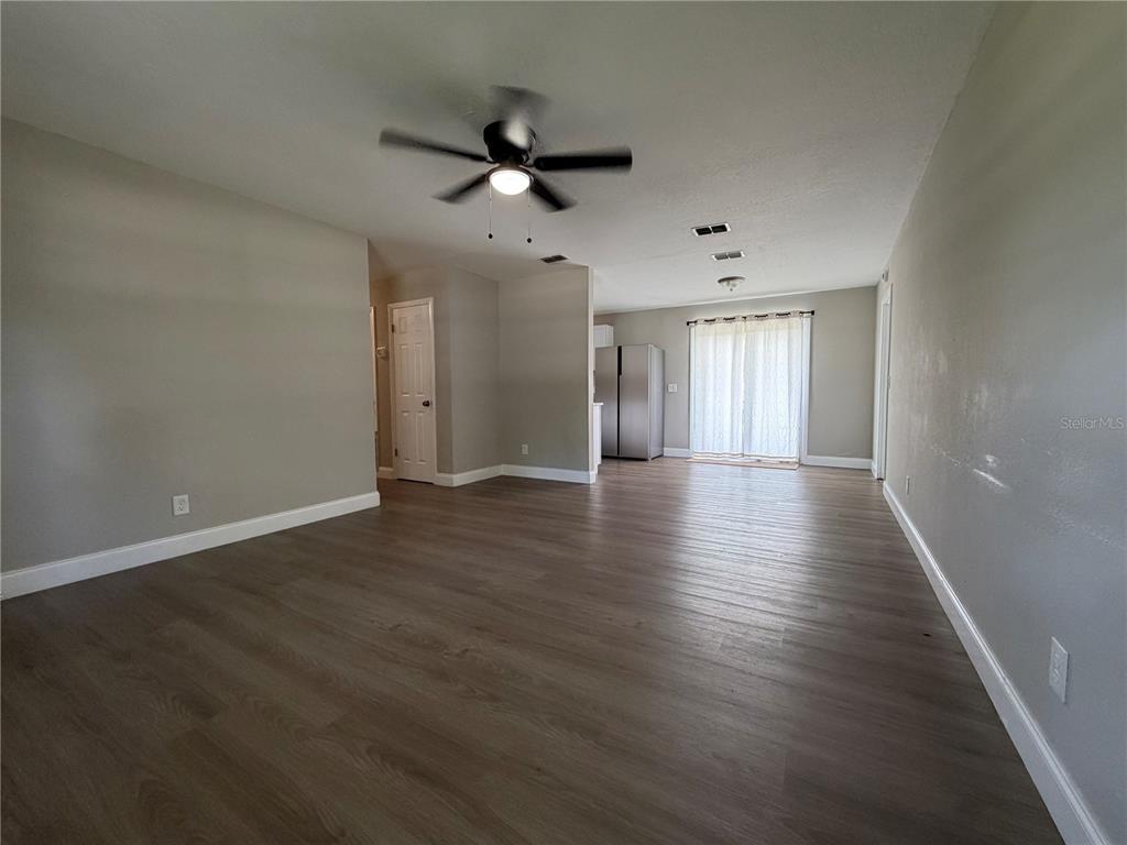 An open-concept living and dining area features gray walls, wood-look flooring, and a ceiling fan — 14109 NEWCOMB AVENUE, ORLANDO, FL