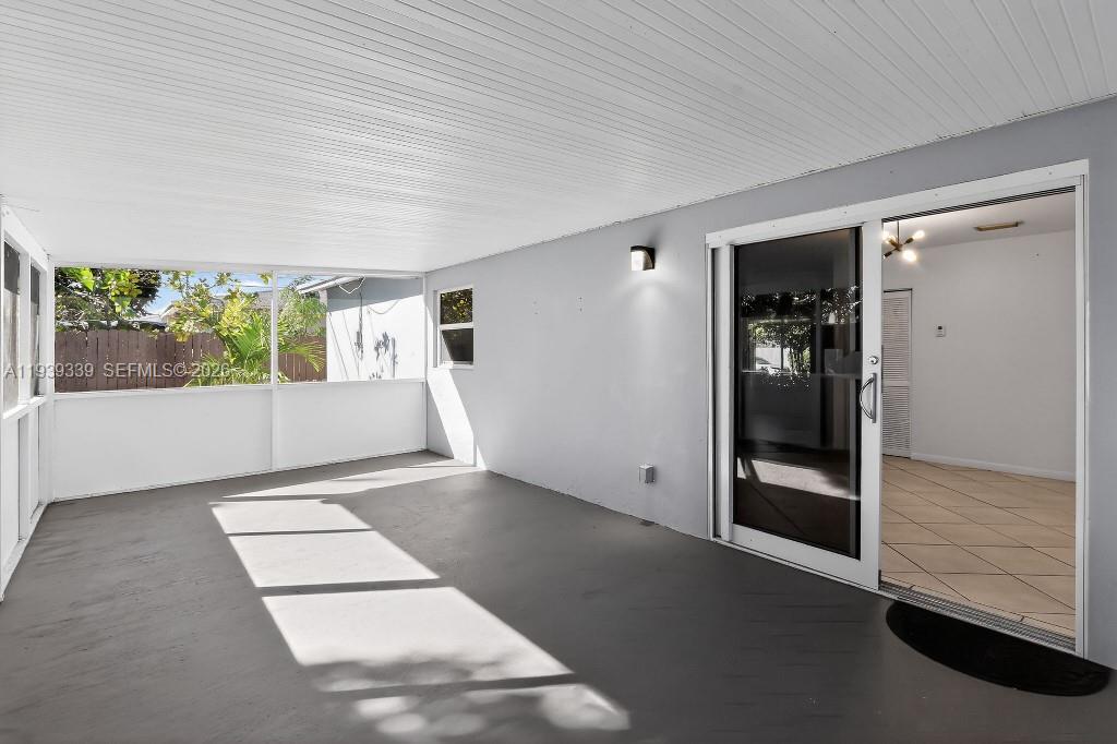 A covered patio with a gray concrete floor, screened walls, and a sliding glass door — 9900 SW 164th Ter, Miami FL 33157, MIAMI, FL