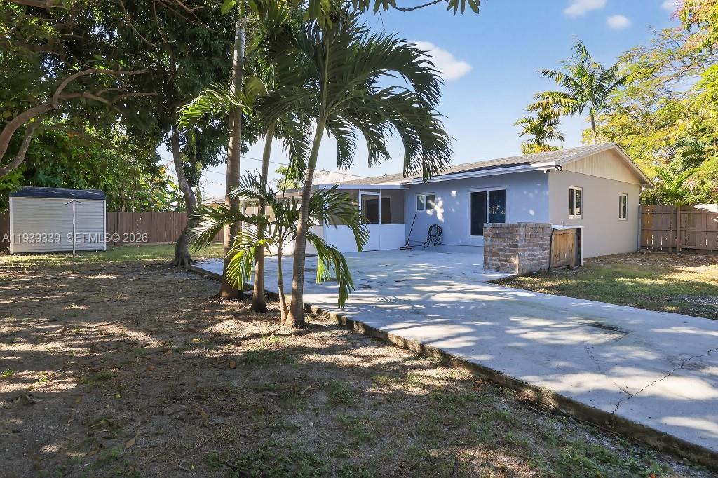 The backyard features a concrete patio, palm trees, a storage shed, and a house exterior — 9900 SW 164th Ter, Miami FL 33157, MIAMI, FL
