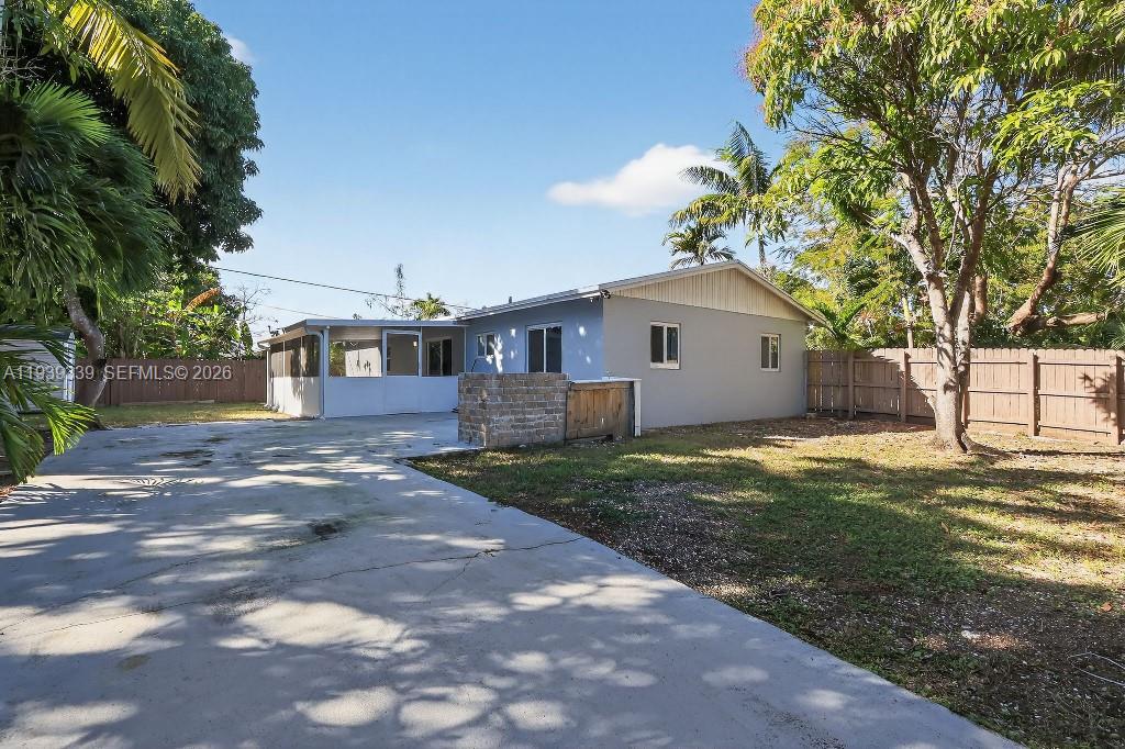 The exterior of a single-story house features a concrete driveway and a fenced backyard — 9900 SW 164th Ter, Miami FL 33157, MIAMI, FL