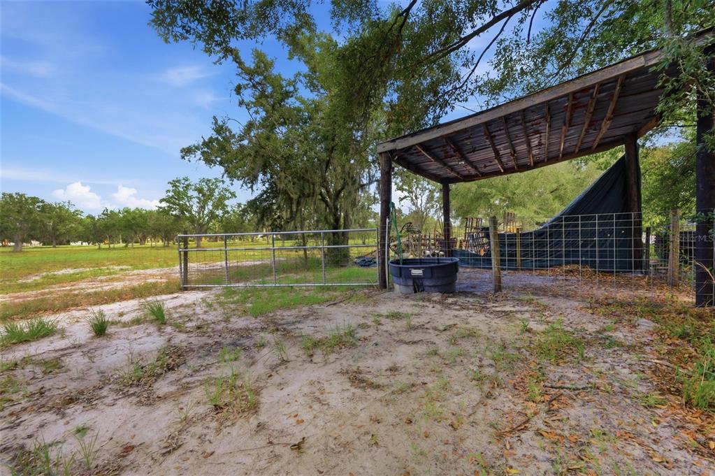 A metal-roofed shelter stands next to a wire fence on a sandy, grassy lot — 6096 NW CUL DE SAC ROAD, ARCADIA, FL