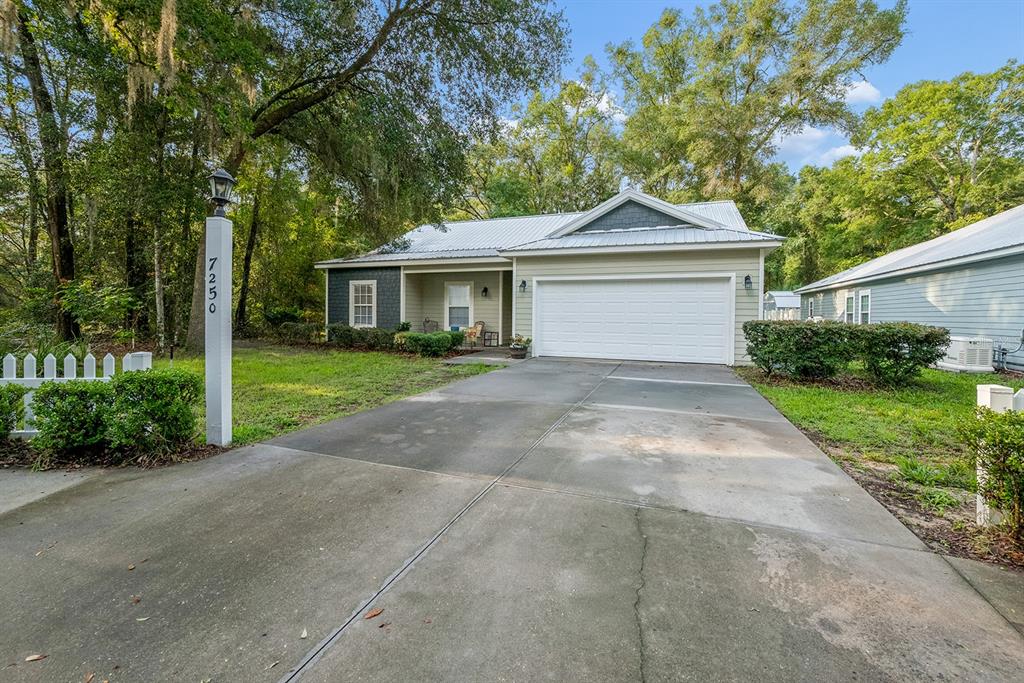 A single-story house with a metal roof, white garage door, and a concrete driveway — 7250 CARDINAL TRAIL, FANNING SPRINGS, FL