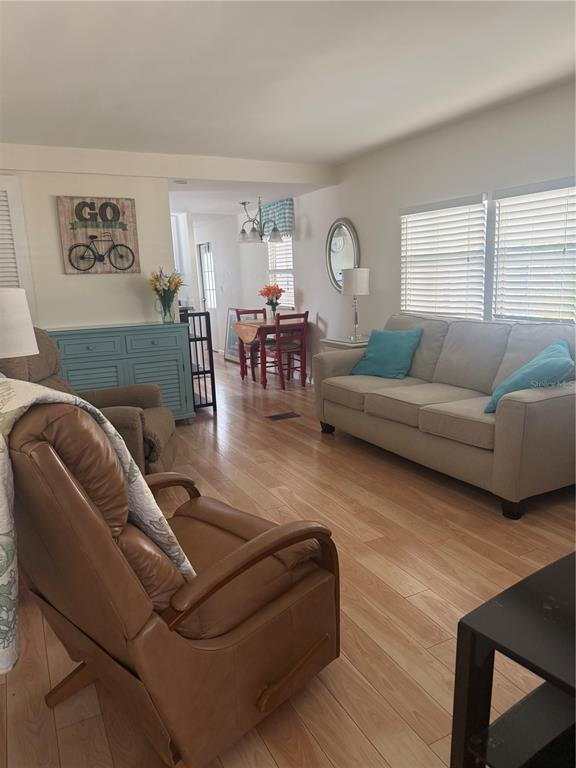 A living room with light wood flooring, a beige sofa, and a brown leather recliner — 716 CAREFREE, VENICE, FL