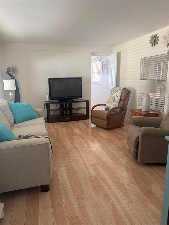 A living room features light wood flooring, a sofa, two armchairs, and a television console — 716 CAREFREE, VENICE, FL