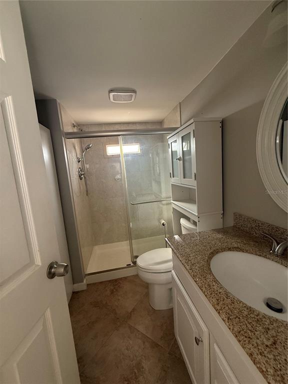 A bathroom features a granite-topped vanity, a toilet, and a glass-enclosed walk-in shower — 716 CAREFREE, VENICE, FL