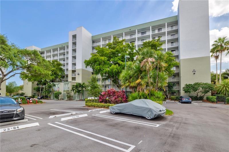 A multi-story apartment building features a parking lot with marked spaces in the foreground — 2240 N Cypress Bend Drive # 802, Pompano Beach FL 33069, POMPANO BEACH, FL