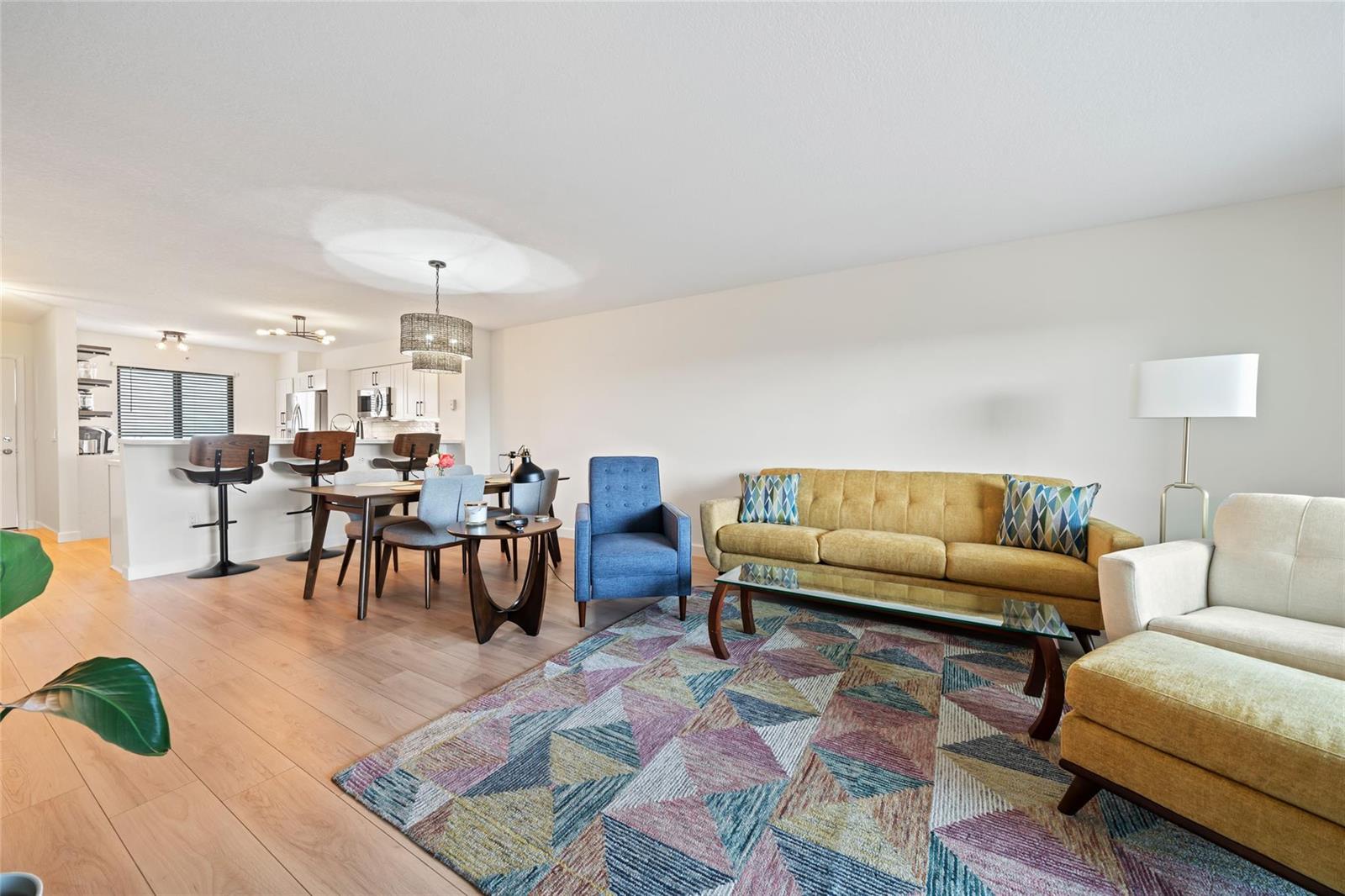 A living room and dining area feature light wood floors, a patterned rug, and furniture — 2240 N Cypress Bend Drive # 802, Pompano Beach FL 33069, POMPANO BEACH, FL