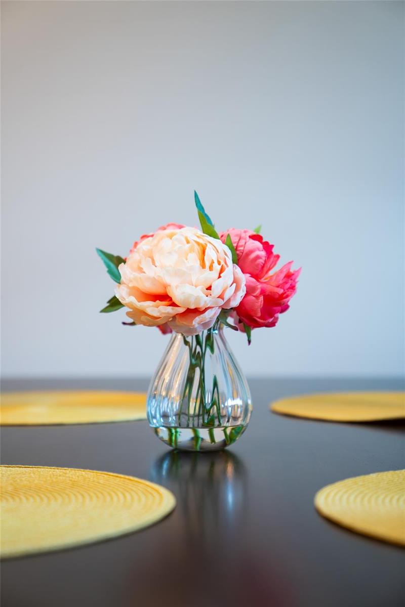 A small glass vase with pink and peach flowers sits on a dark table — 2240 N Cypress Bend Drive # 802, Pompano Beach FL 33069, POMPANO BEACH, FL