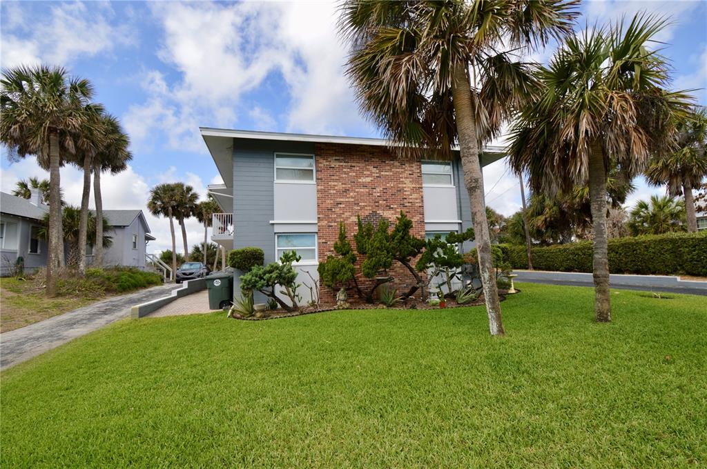 A two-story building with a brick facade and gray siding stands behind a grassy lawn — 835 N GRANDVIEW AVENUE, DAYTONA BEACH, FL