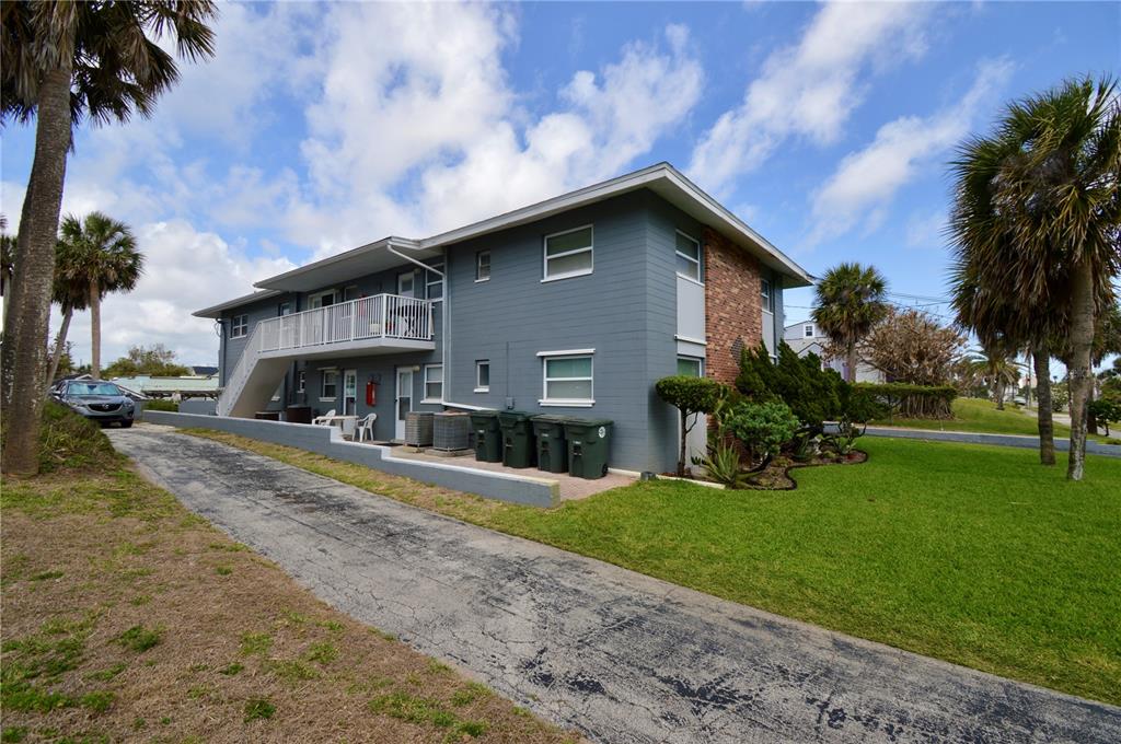 A two-story gray apartment building with a balcony, exterior staircase, and a paved driveway — 835 N GRANDVIEW AVENUE, DAYTONA BEACH, FL
