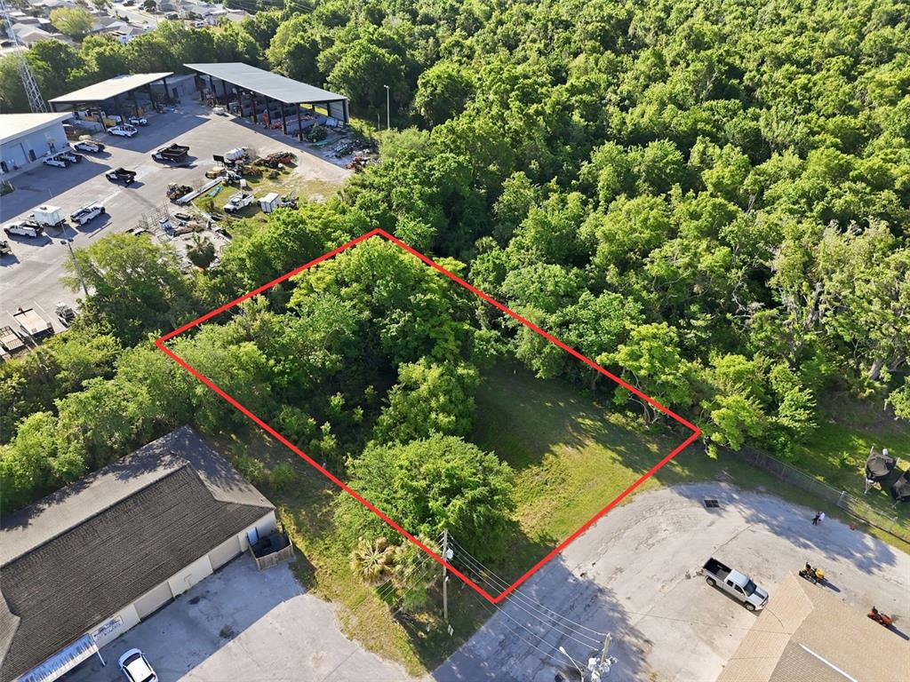 An aerial view shows a rectangular, tree-covered vacant lot outlined in red — 7810 CLARK MOODY BOULEVARD, PORT RICHEY, FL
