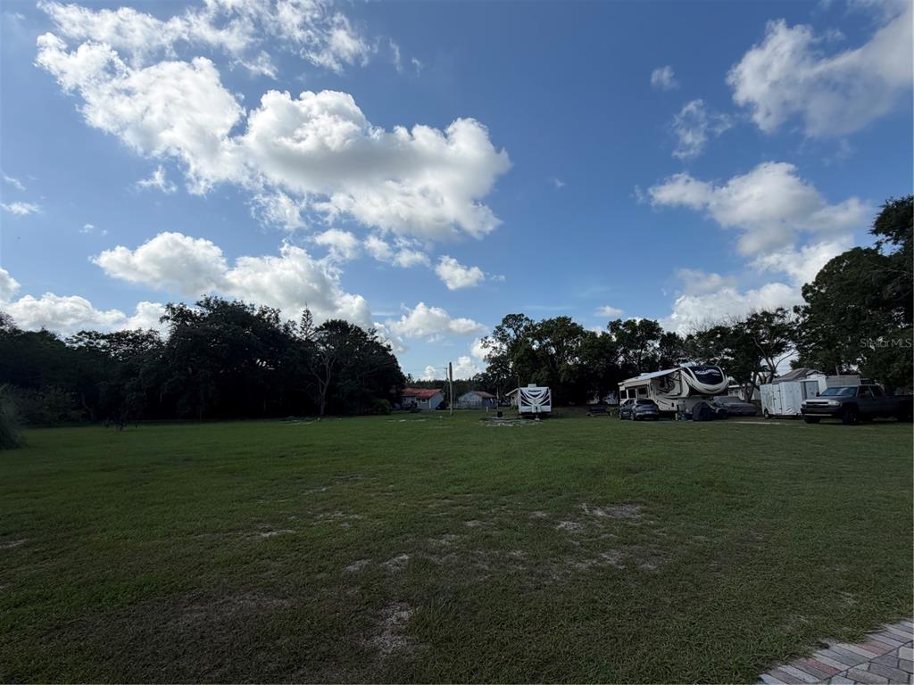 A large, grassy lot features several parked recreational vehicles and a truck under a blue sky — 3900 CHALET SUZANNE DRIVE, LAKE WALES, FL