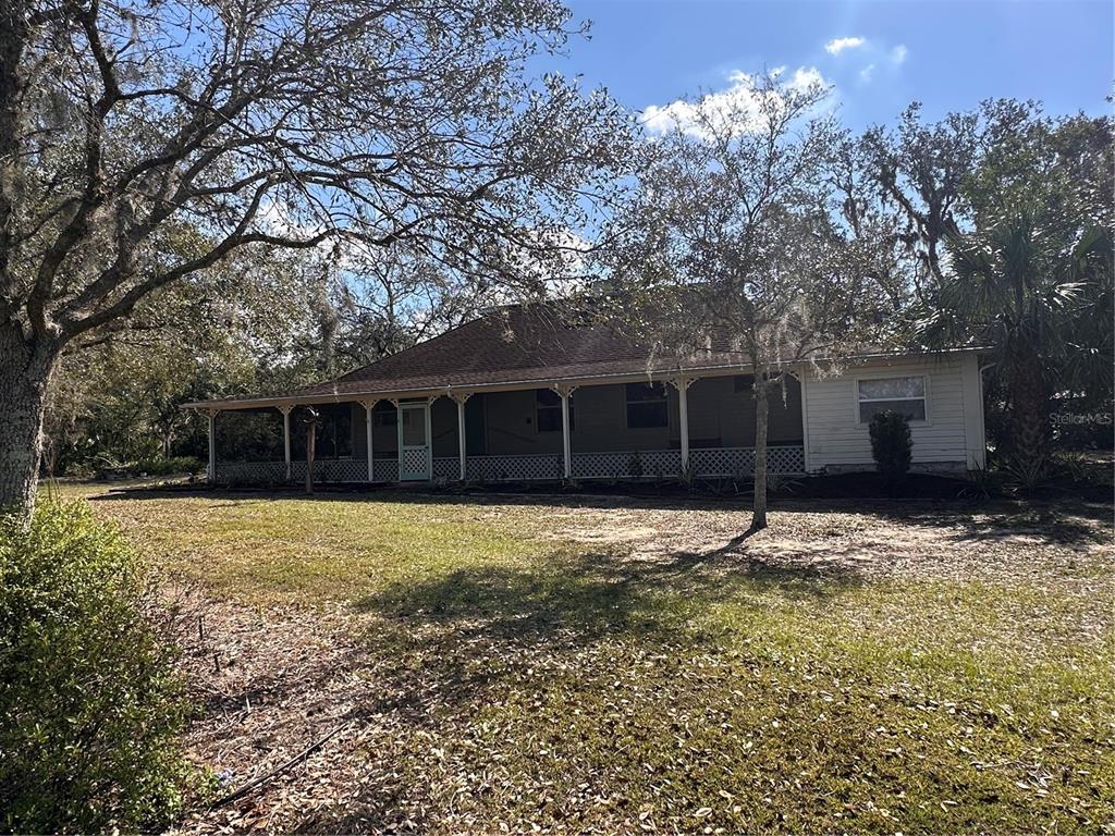 A single-story house with a wide, covered front porch and lattice skirting under trees — 3900 CHALET SUZANNE DRIVE, LAKE WALES, FL