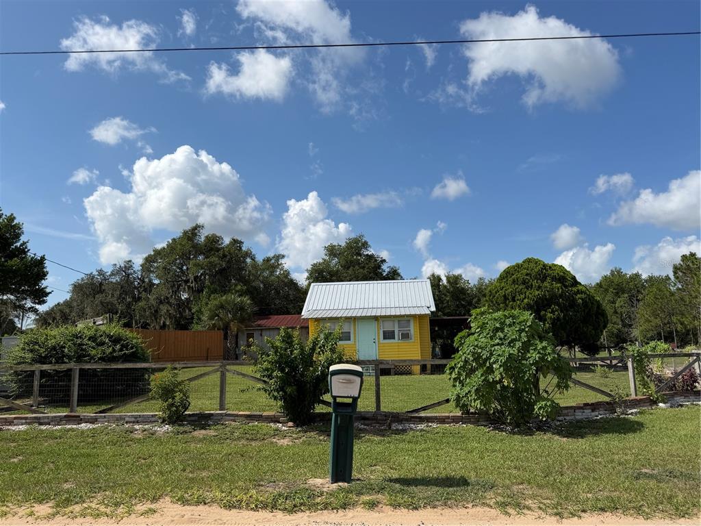 A small yellow house with a metal roof sits behind a wooden fence — 3900 CHALET SUZANNE DRIVE, LAKE WALES, FL