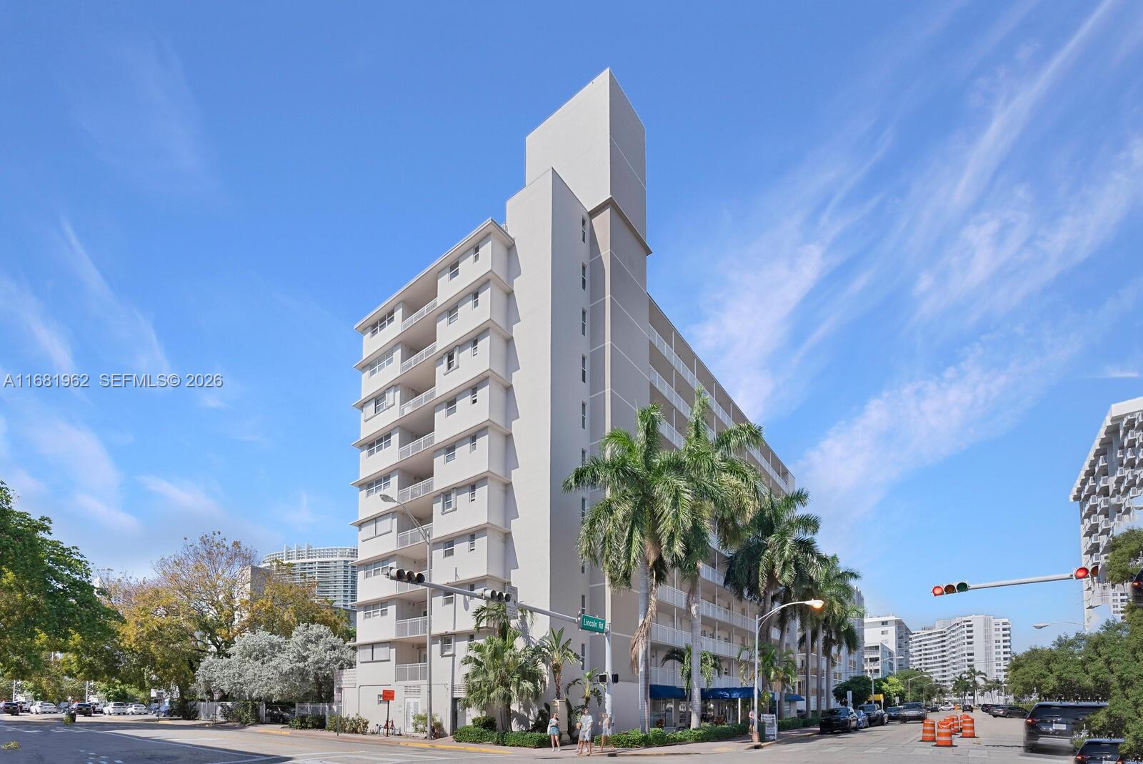A tall, light-colored apartment building stands on a street corner with palm trees — 1300 Lincoln Rd # A701, Miami Beach FL 33139, MIAMI BEACH, FL