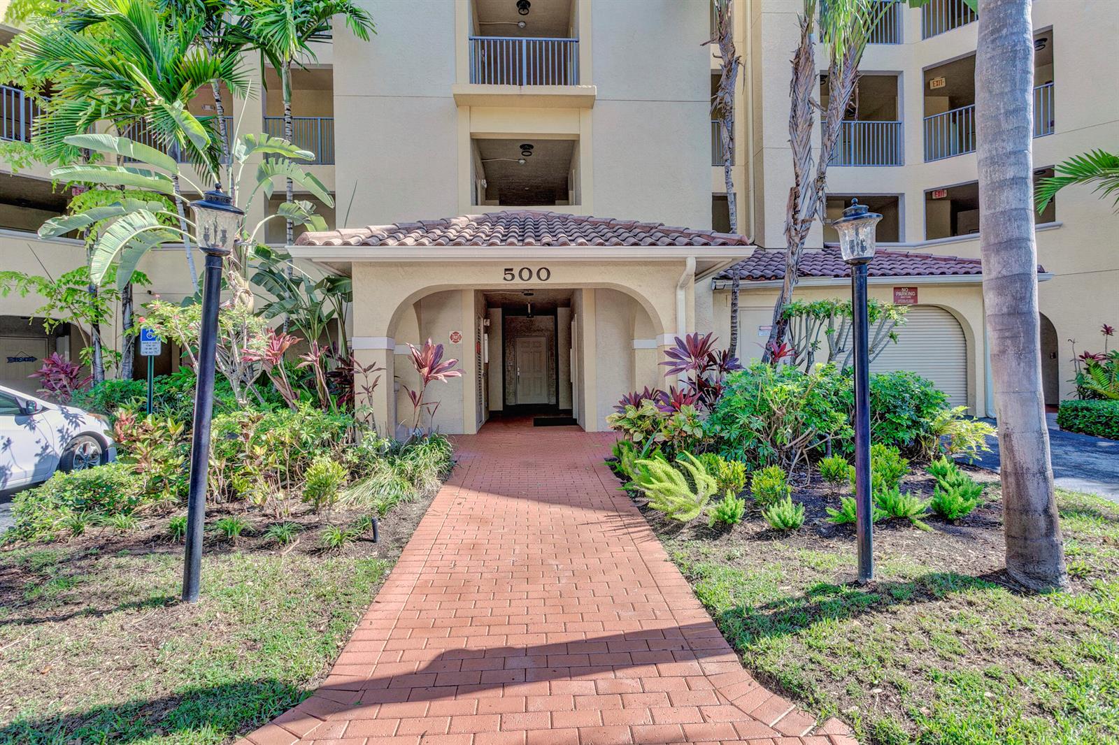 A brick walkway leads to the covered entrance of a multi-story apartment building — 500 Uno Lago Drive # 402, Juno Beach FL 33408, JUNO BEACH, FL