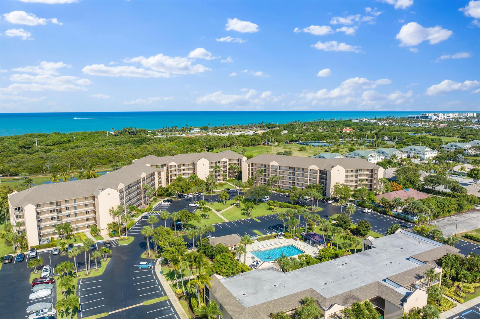 An aerial view shows multi-story residential buildings surrounding a central parking lot and swimming pool — 275 Palm Avenue # A302, Jupiter FL 33477, JUPITER, FL