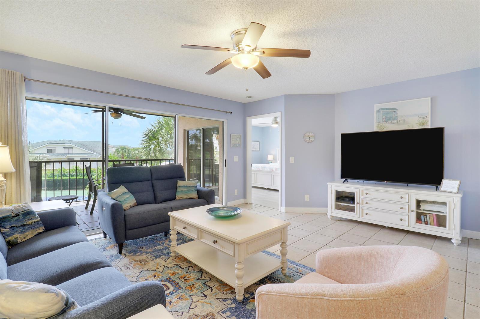 A living room features blue sofas, a white coffee table, and a television on a stand — 275 Palm Avenue # A302, Jupiter FL 33477, JUPITER, FL