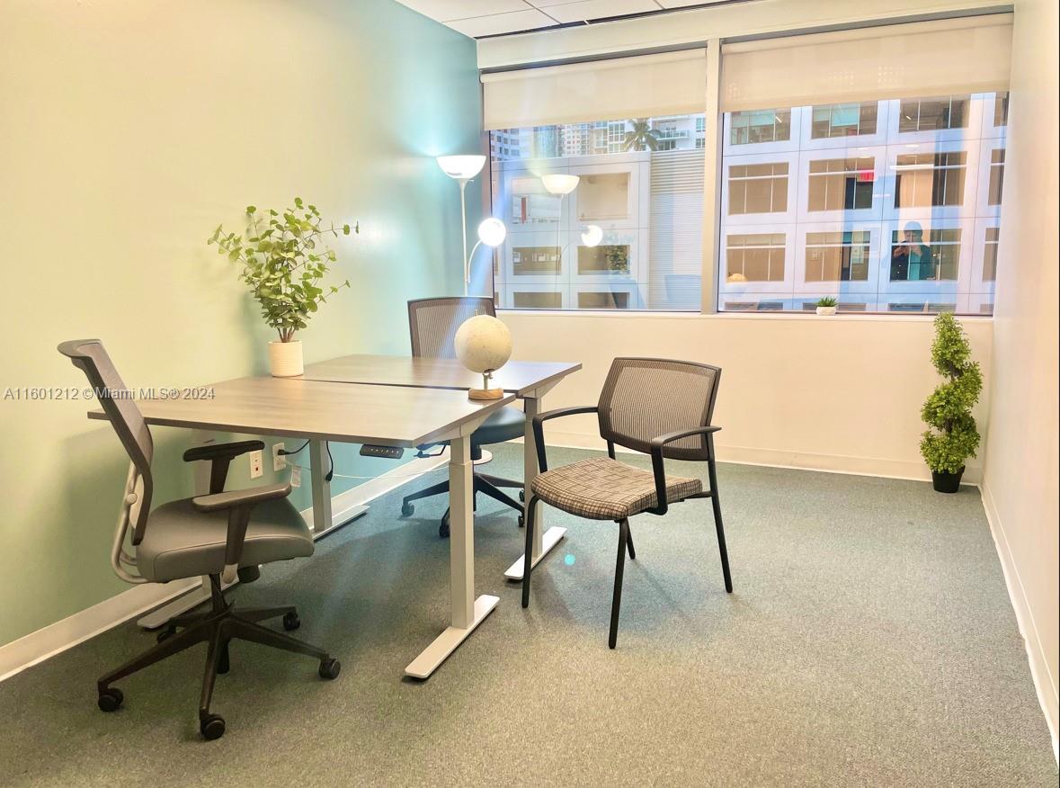 An office space features a desk, two chairs, a globe, and a large window — 777 Brickell Ave, Miami FL 33131, MIAMI, FL