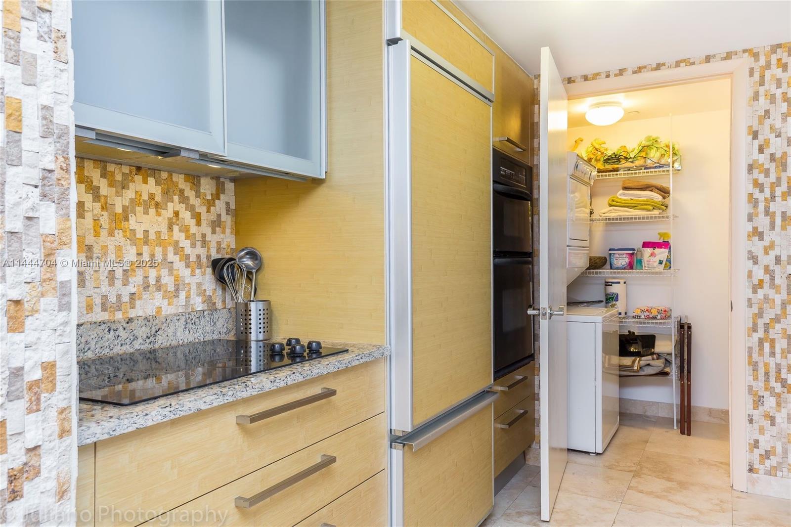 A kitchen features light wood cabinetry, a granite countertop, a glass cooktop, and mosaic tiling — 1830 S Ocean Dr # 1107, Hallandale Beach FL 33009, HALLANDALE BEACH, FL