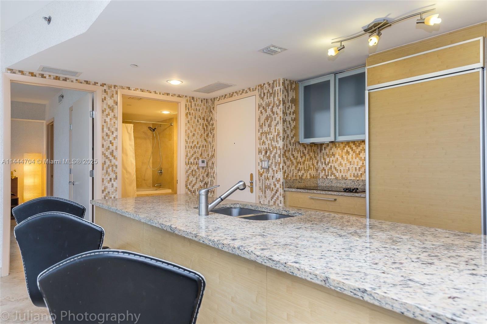 A kitchen features light wood cabinetry, a granite countertop, and an adjacent laundry closet — 1830 S Ocean Dr # 1107, Hallandale Beach FL 33009, HALLANDALE BEACH, FL