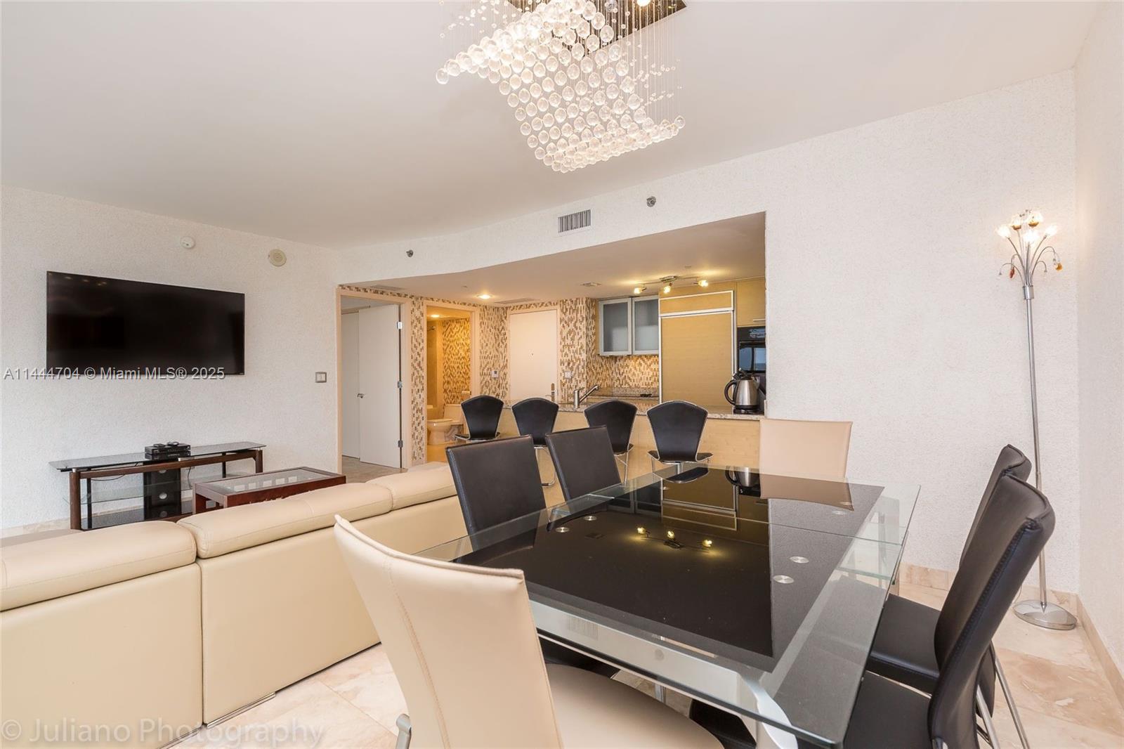 A kitchen features a granite island, light wood cabinetry, and a mosaic tile backsplash — 1830 S Ocean Dr # 1107, Hallandale Beach FL 33009, HALLANDALE BEACH, FL