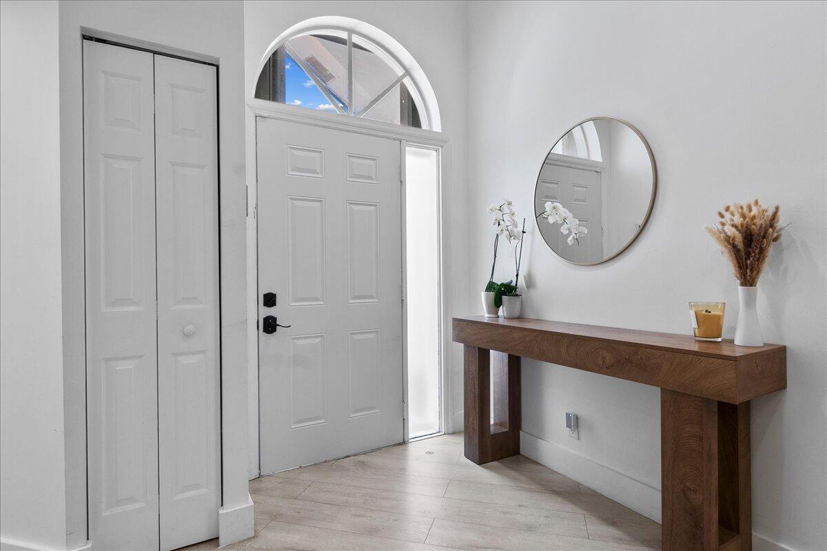 A bright entryway features a white front door, a wooden console table, and light flooring — 8304 Vía Di Veneto, Boca Raton FL 33496, BOCA RATON, FL