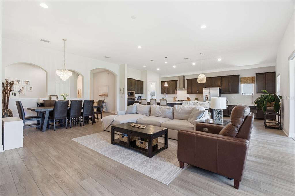 An open-concept living room and dining area with dark wood cabinets and light flooring — 5604 WAYFARER AVENUE, APOLLO BEACH, FL