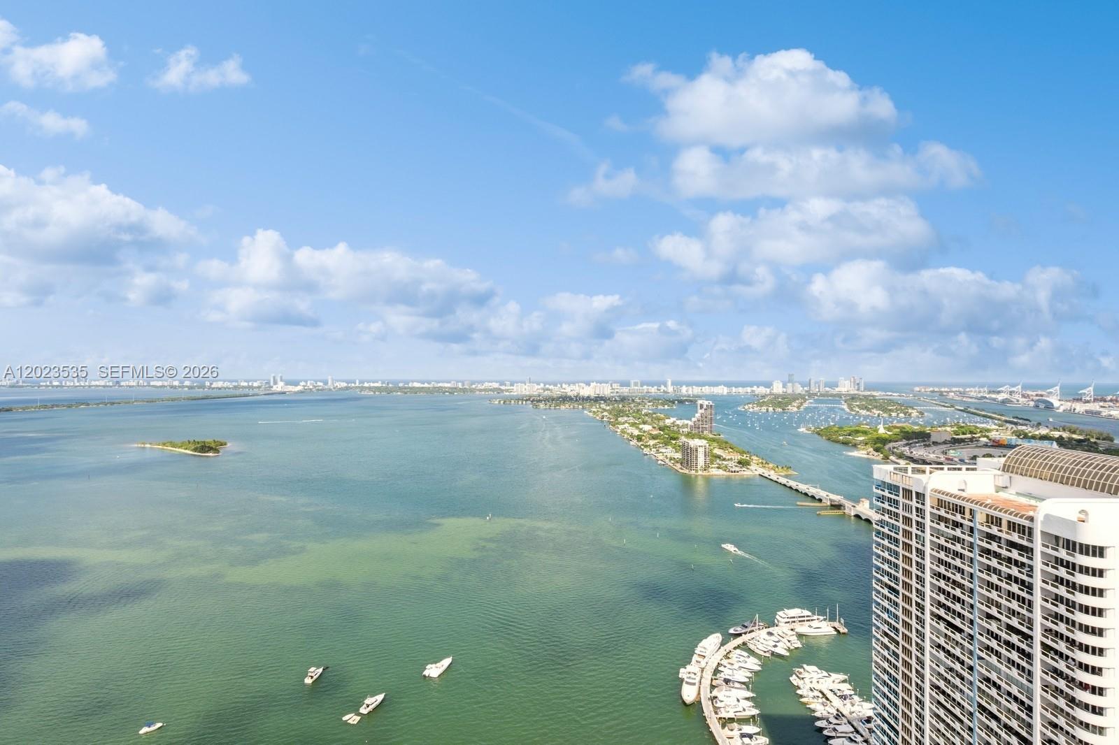 An aerial view shows a bay with islands, a bridge, boats, and a high-rise building — 1750 N Bayshore Dr # 4702, Miami FL 33132, MIAMI, FL