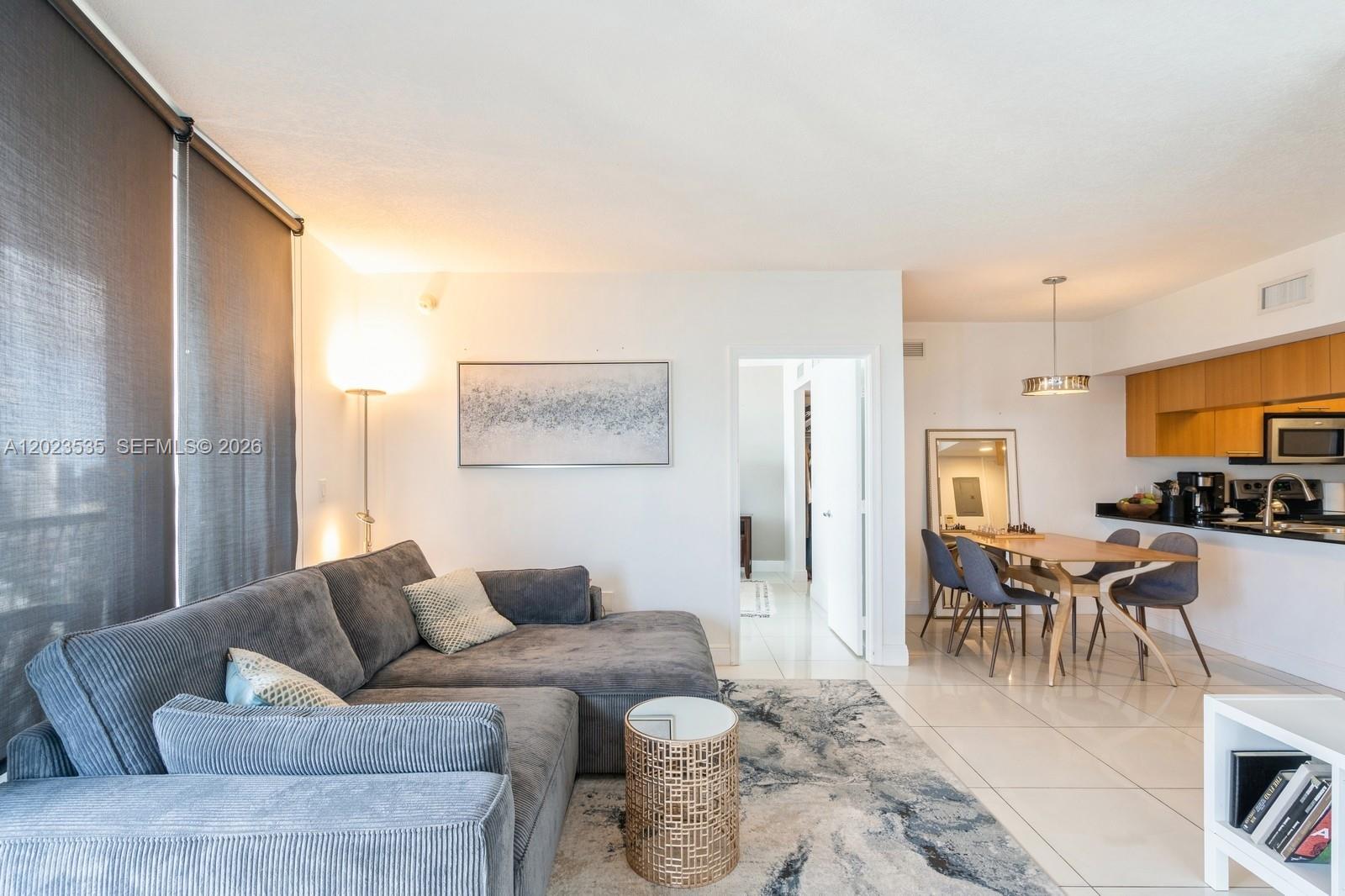 A living room with a grey sectional sofa, dining area, and kitchen with wood cabinets — 1750 N Bayshore Dr # 4702, Miami FL 33132, MIAMI, FL