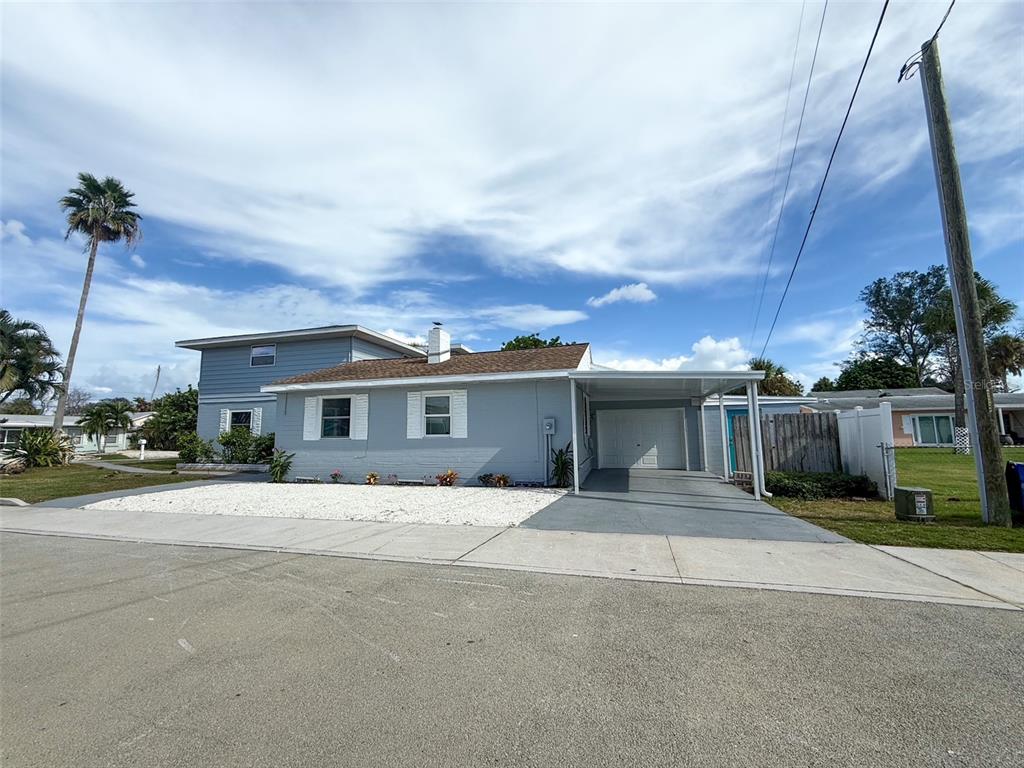 A light blue single-story house with a white gravel yard and an attached carport — 13290 3RD STREET E, MADEIRA BEACH, FL