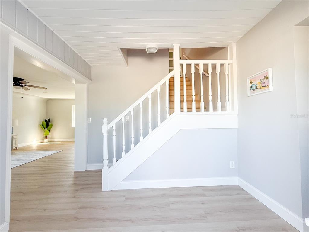 A white staircase with wooden treads stands in a room with light wood-look flooring — 13290 3RD STREET E, MADEIRA BEACH, FL