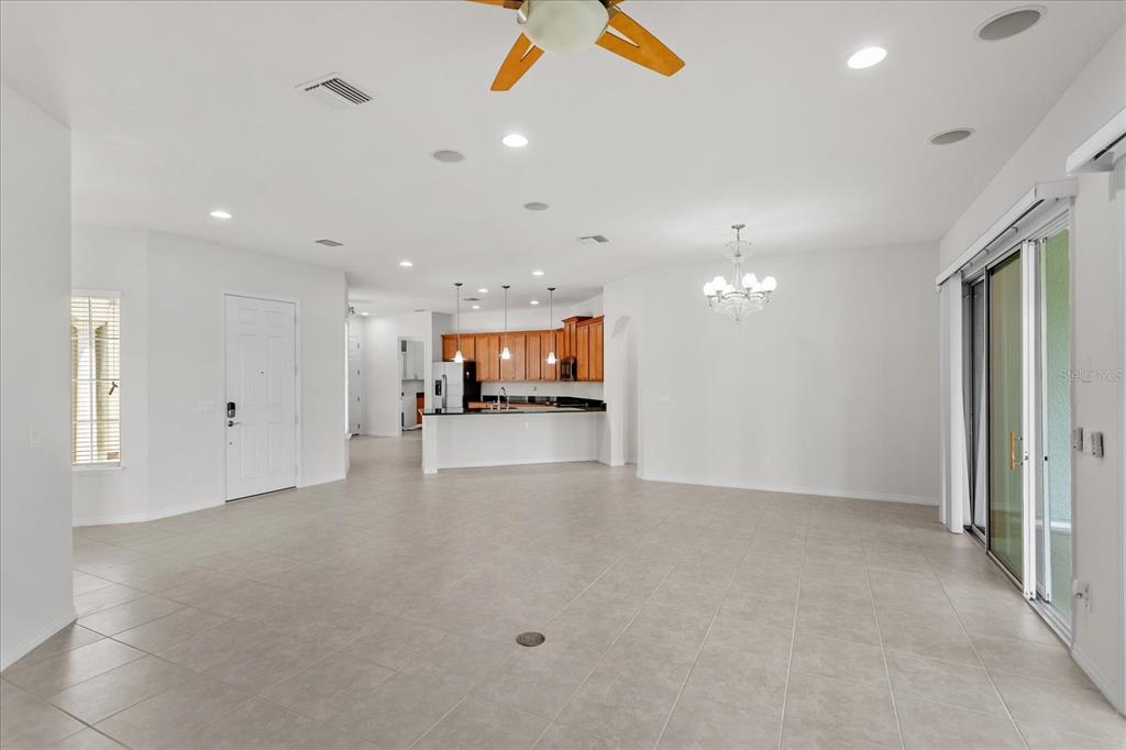 An open-concept living area features tile flooring, a kitchen with wood cabinets, and sliding doors — 124 BALMY COAST ROAD, GROVELAND, FL